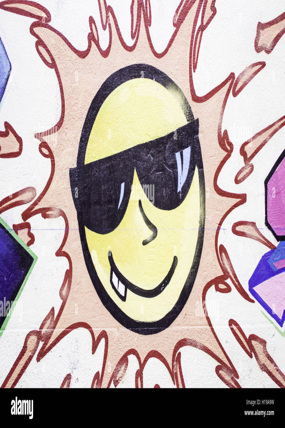 Graffiti sun with sunglasses on city street, decoration Stock